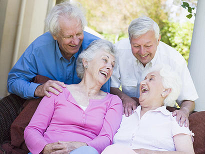 Group of senior friends sitting on garden seat laughing